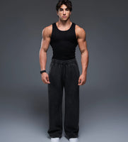 Man wearing a black tank top and black pants on a gray background
